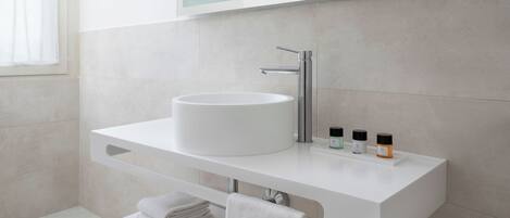 A modern bathroom with a white vanity, a round sink, a mirror, and a towel rack.