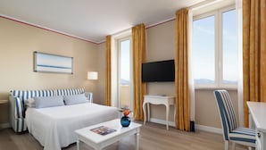 Una habitación de hotel con una cama, televisión, escritorio y silla.