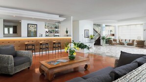 A modern hotel lobby with a bar area, seating arrangements, and a staircase leading to an upper floor. - Sina Astor (Viareggio)
