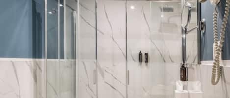 A modern bathroom with a glass-enclosed shower, a large sink, and a vanity with toiletries.