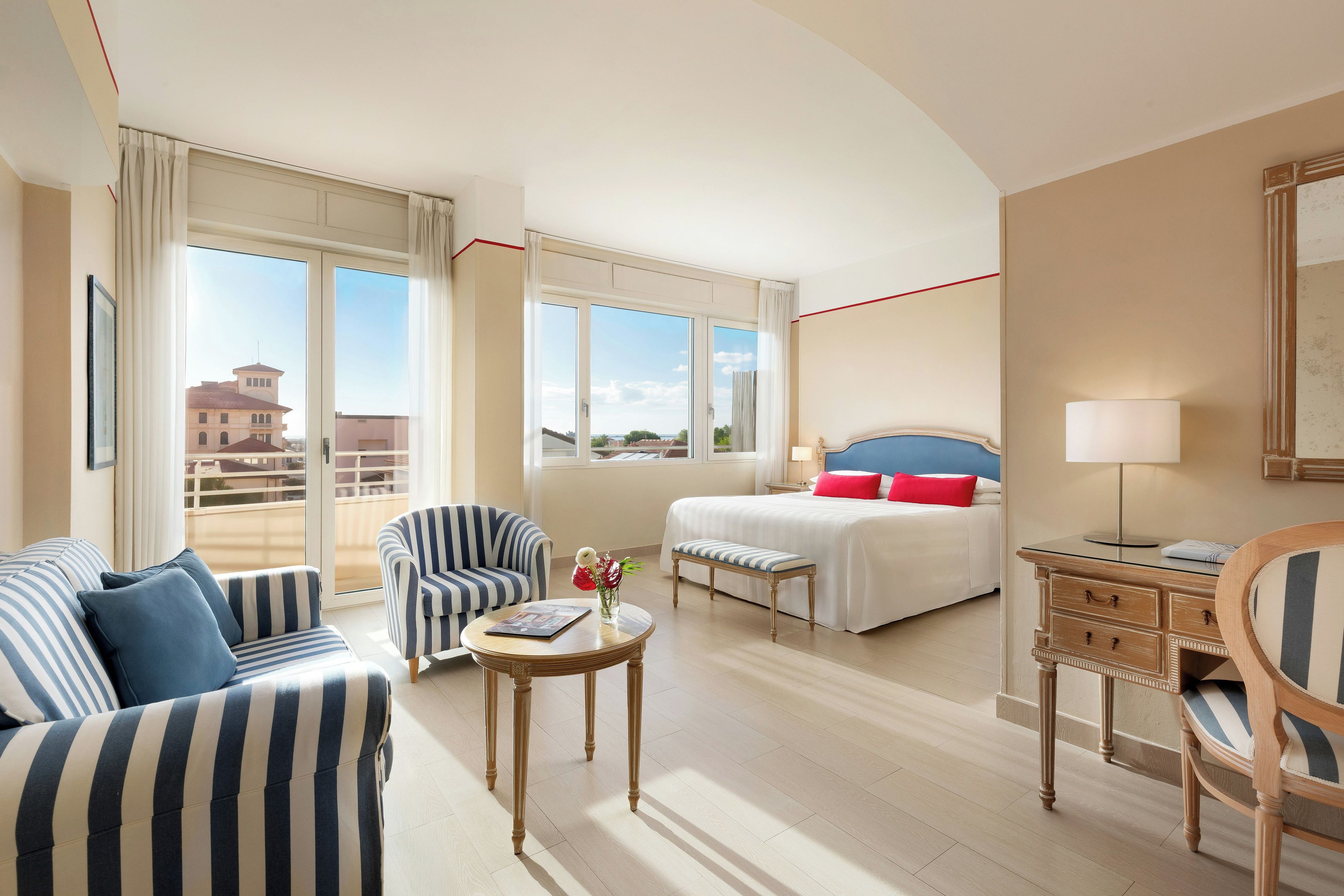A hotel room with a bed, a sofa, a chair, a table, and a lamp.