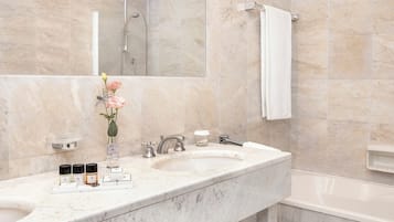 A bathroom with a marble sink, a mirror, a shower, and a bathtub.
