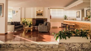 A spacious living area with a fireplace, comfortable seating, and a marble floor. - Sina Astor (Viareggio)