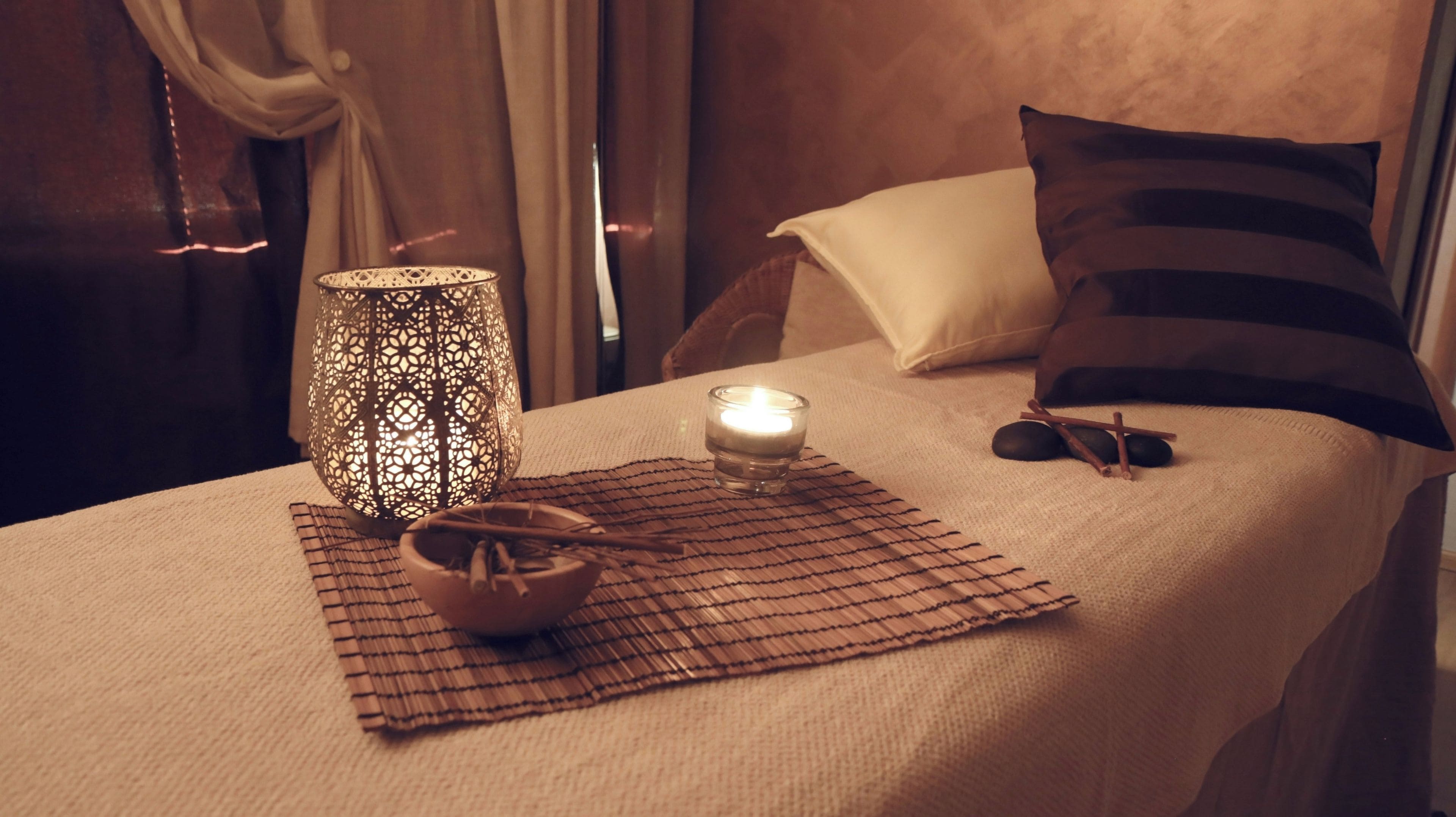 Une chambre à coucher bien rangée, avec un lit, une lampe décorative, une bougie et un tapis.