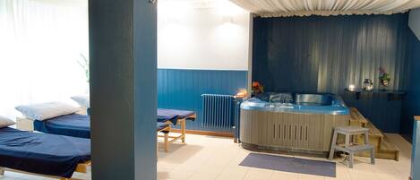Una habitación con dos camas, una mesa de masaje, una sauna y un radiador.