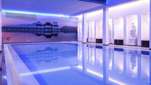 A modern indoor pool with clear water, surrounded by white walls and illuminated by blue lighting. - Sina Astor (Viareggio)