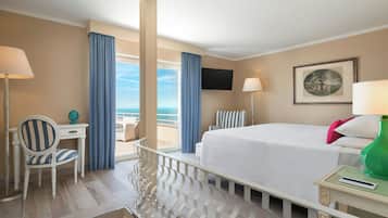 A hotel room with a bed, a desk, a chair, a TV, and a balcony with curtains.
