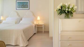 Una habitación de hotel con cama, mesitas de noche, cómoda, silla y un cuadro en la pared.
