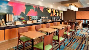 A modern hotel lobby with a long counter, multiple seating areas, and a colorful abstract mural on the wall.