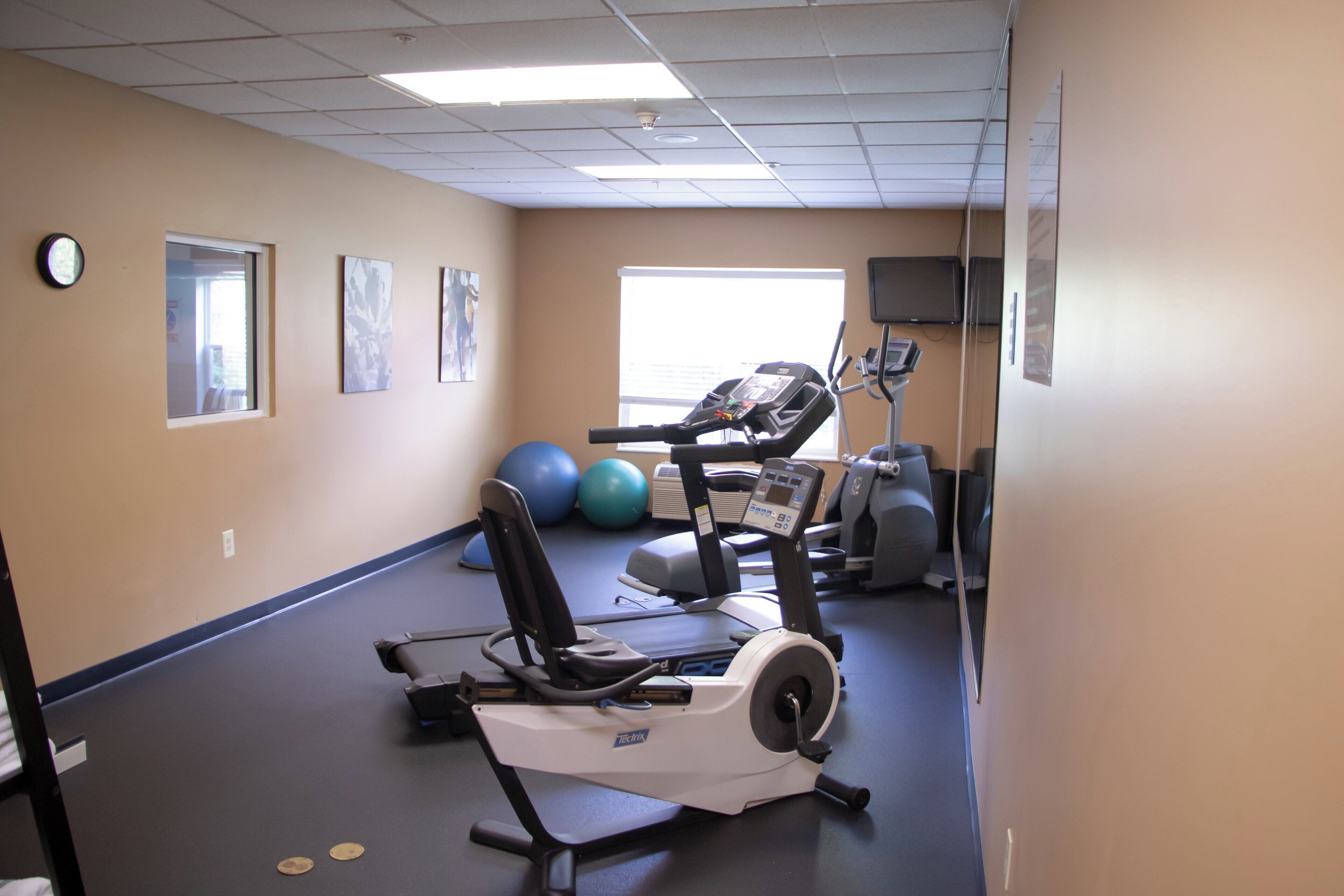 Egy fitneszterem kardioeszközökkel, gimnasztikai labdákkal és futópadokkal felszerelve.