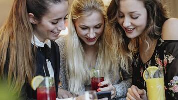 Três pessoas sentadas à mesa com bebidas e petiscos.