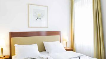Une chambre d’hôtel avec un lit, un tableau encadré au mur, une lampe de chevet et une fenêtre avec des rideaux.