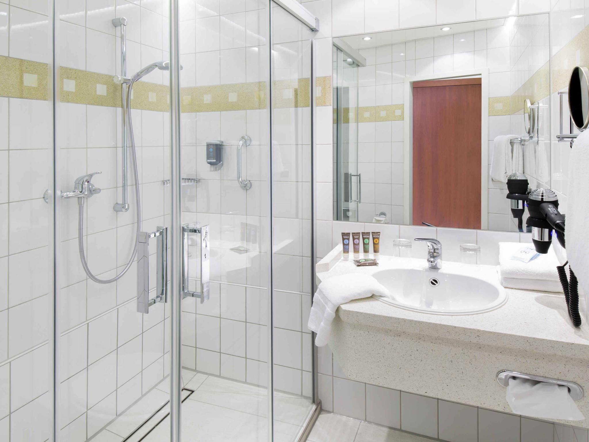 Un bagno moderno con doccia vetro, lavandino e specchio, e articoli da toilette.