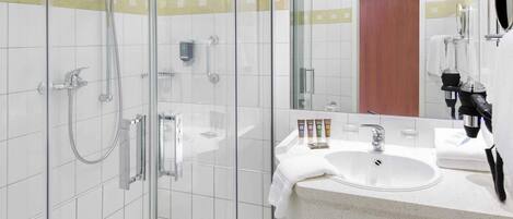 Un bagno moderno con doccia vetro, lavandino e specchio, e articoli da toilette.