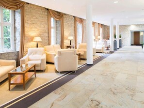 A hotel lobby with a stone wall, multiple seating areas, and a long corridor. -  Sunday Hotel Hildesheim Zentrum (Hildesheim)