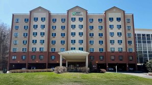 Un hotel de varios pisos con una entrada central y un área de espera techada.