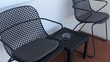 Dos sillas de malla negra con asientos y respaldos acolchados, una pequeña mesa negra y un vaso sobre la mesa.