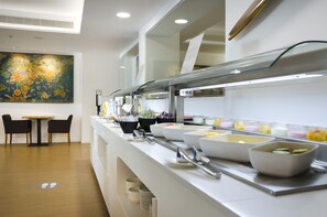 Un espace buffet proposant une variété de plats, un tableau accroché au mur et un coin salon avec des chaises et une table.