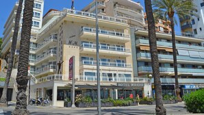 Ein mehrstöckiges Hotel mit Balkonen, Palmen und blauem Himmel.