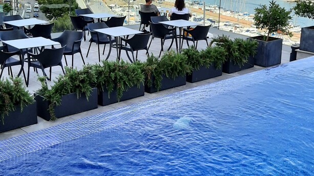 Eine Dachterrasse mit Pool, Essbereich und Blick auf einen Hafen.