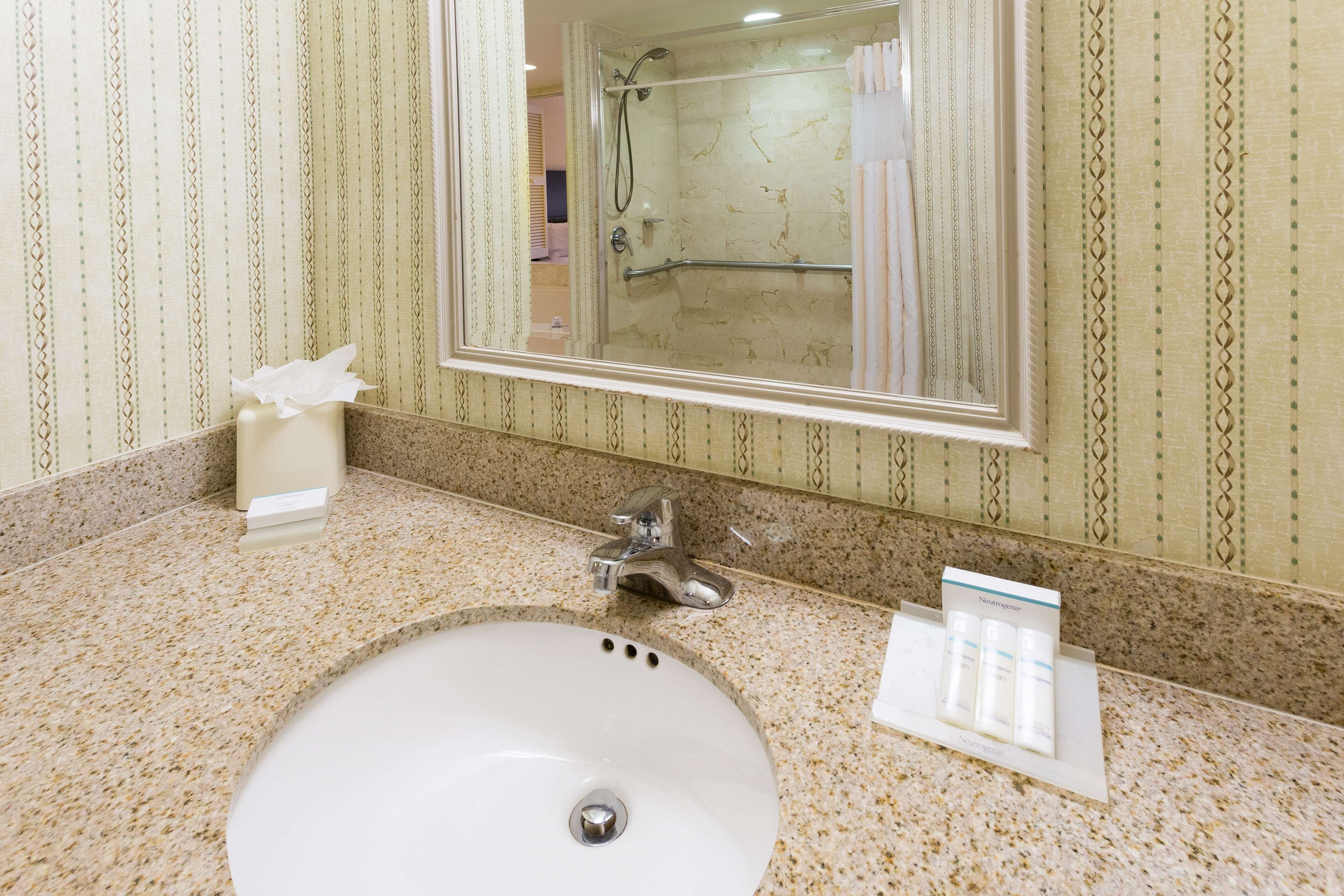 Un baño con lavamanos, espejo y artículos de aseo.