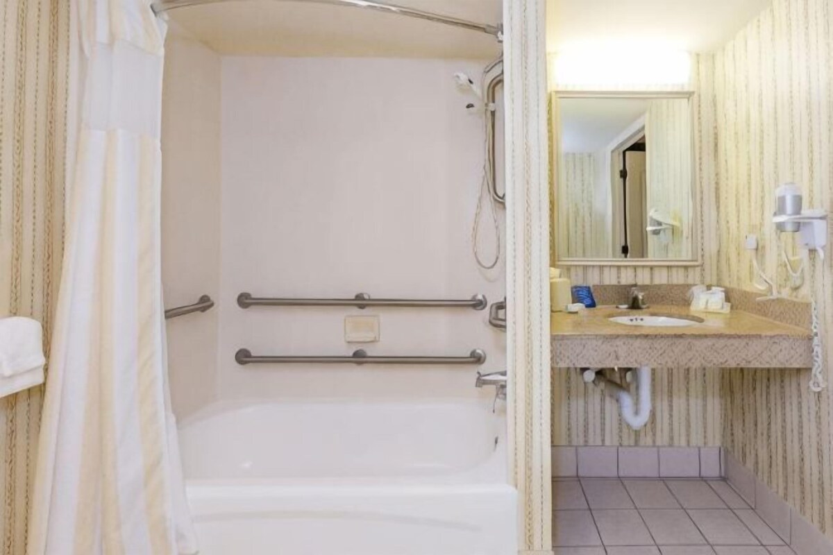 A bathroom with a bathtub, a sink, a mirror, and a shower area.