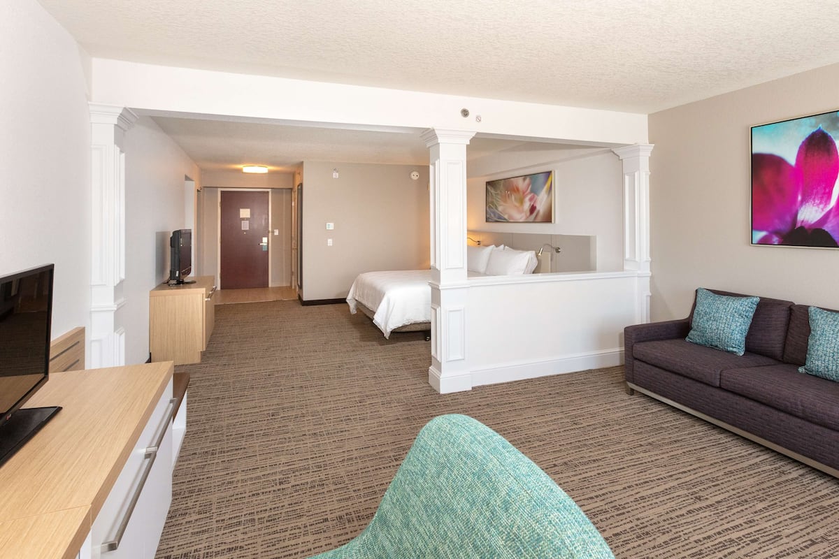 A hotel room with a bed, a sofa, a TV, and a desk.