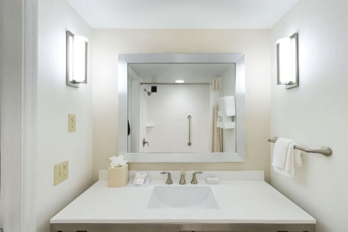 A bathroom with a white sink, a large mirror, and two wall-mounted lights.