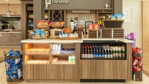 Un puesto de aperitivos y bebidas llamado "The Shop", con diversas opciones de bocadillos, papas fritas y bebidas embotelladas.