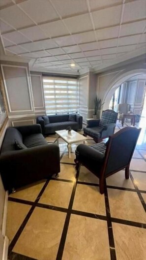 A room with a sectional sofa, two armchairs, a coffee table, and a patterned floor. - Albatros Premier Hotel - Special Class (Istanbul)