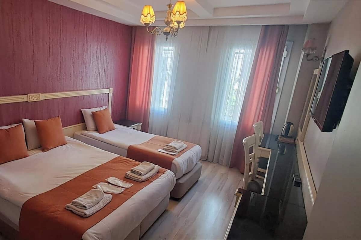 A hotel room with two beds, a wooden headboard, a desk with a chair, and a large mirror.