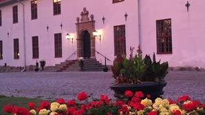 Un edificio de fachada simétrica, con una entrada central escalonada y un cantero de flores al frente.