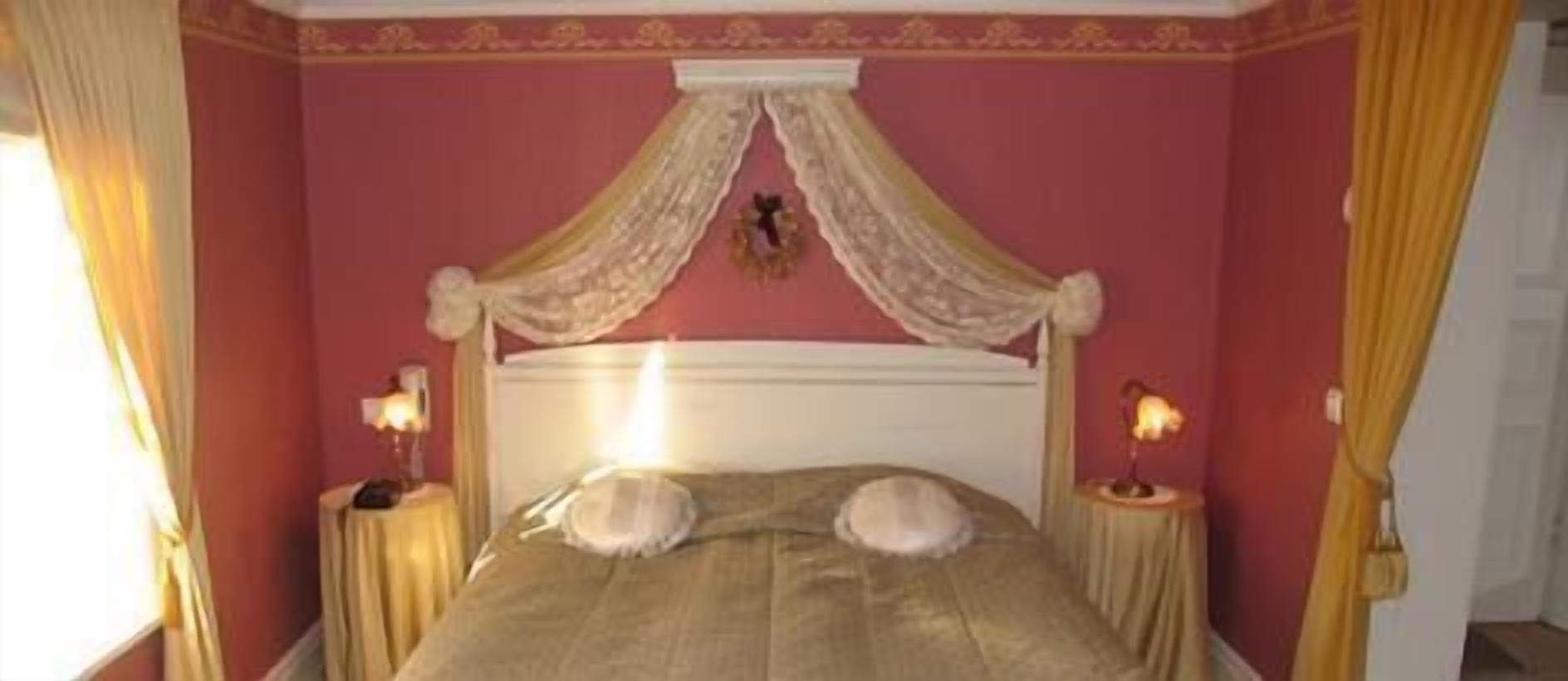A bedroom with a canopy bed, two bedside tables, and a decorative wall hanging.