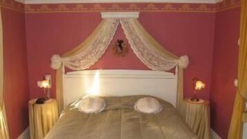A bedroom with a canopy bed, two bedside tables, and a decorative wall hanging.
