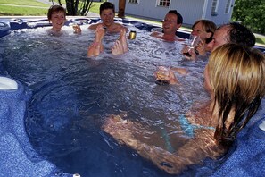 Un grupo de personas en un jacuzzi con burbujas y agua visible.