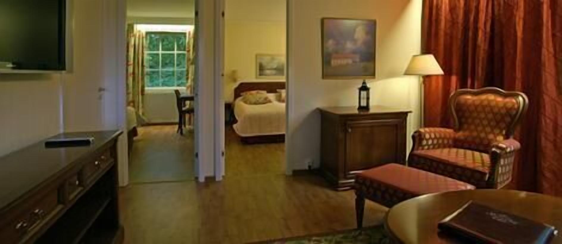 A hotel room with a bed, a chair, a table, a lamp, and a television.