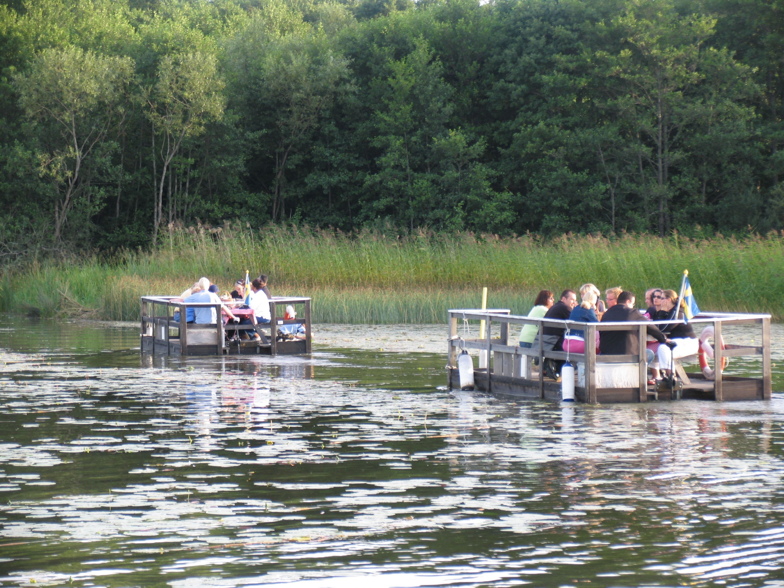 Two wooden boats with people on them, floating on calm water.