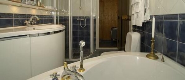 Un baño con bañera, lavabo y zona de ducha.