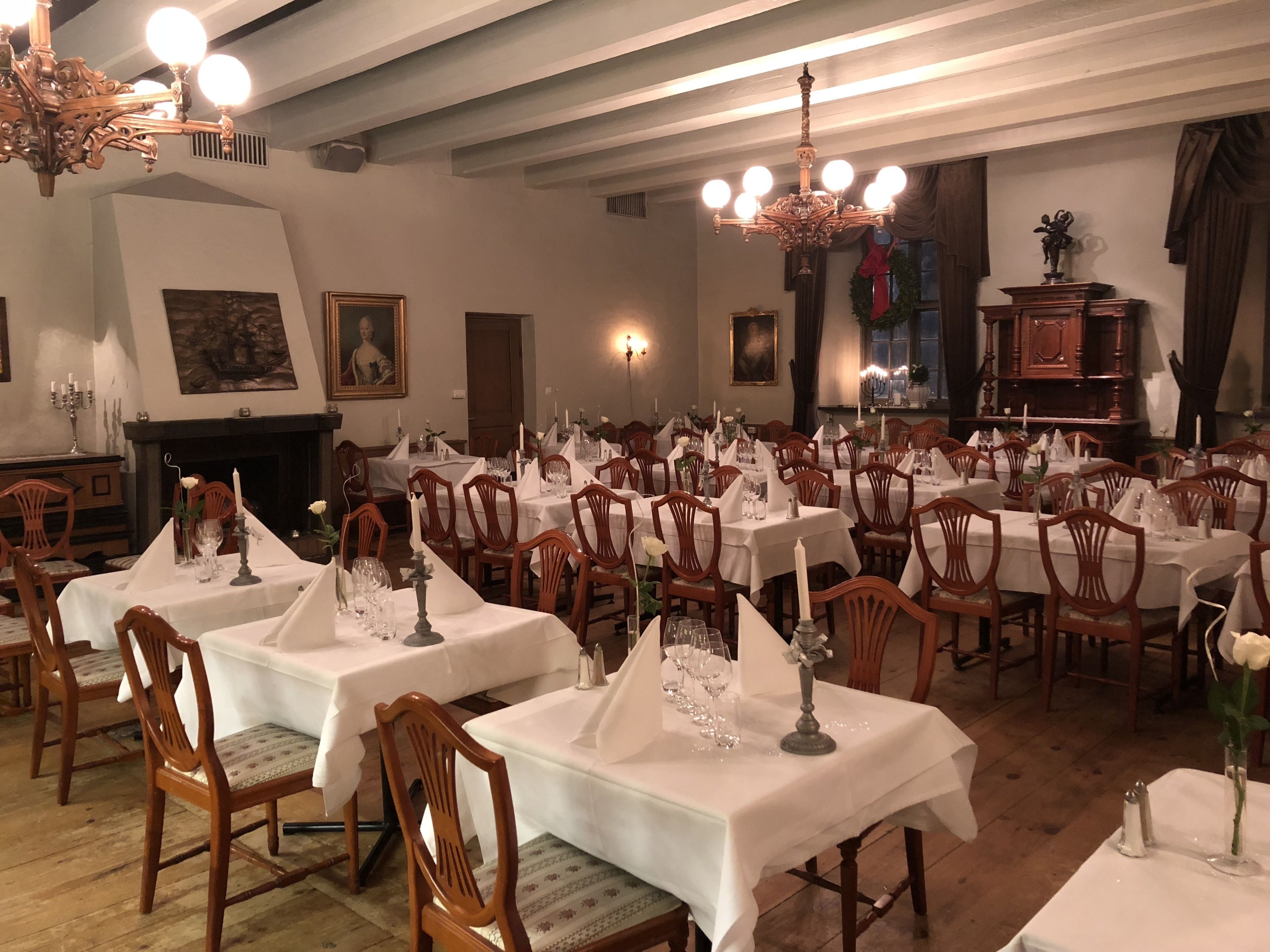 Un comedor formal con varias mesas dispuestas para el servicio, sillas de madera y candelabros.