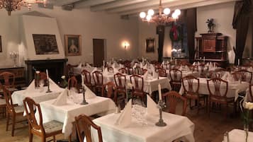 Un comedor formal con varias mesas dispuestas para el servicio, sillas de madera y candelabros.