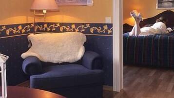 Relax in a serene space with a plush armchair, a cozy table, and a comfortable bed.