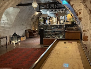 A cozy interior with a red carpet, a wooden bench, and a display case with bottles. - Sundbyholms Slott (Eskilstuna)