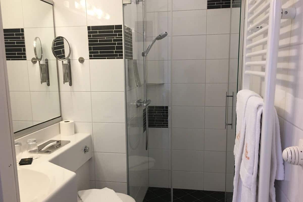 A bathroom with a glass-enclosed shower, a white sink, and a mirror.