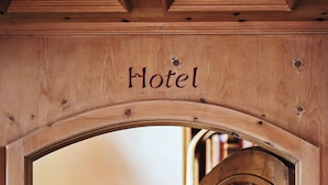 A wooden arched doorway with the word "Hotel" above it, leading to a staircase with red steps. - Hotel Chesa Grischuna (Klosters-Serneus)