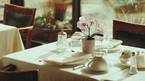 Mesa de comedor para dos con vistas a un jardín a través de grandes ventanales.