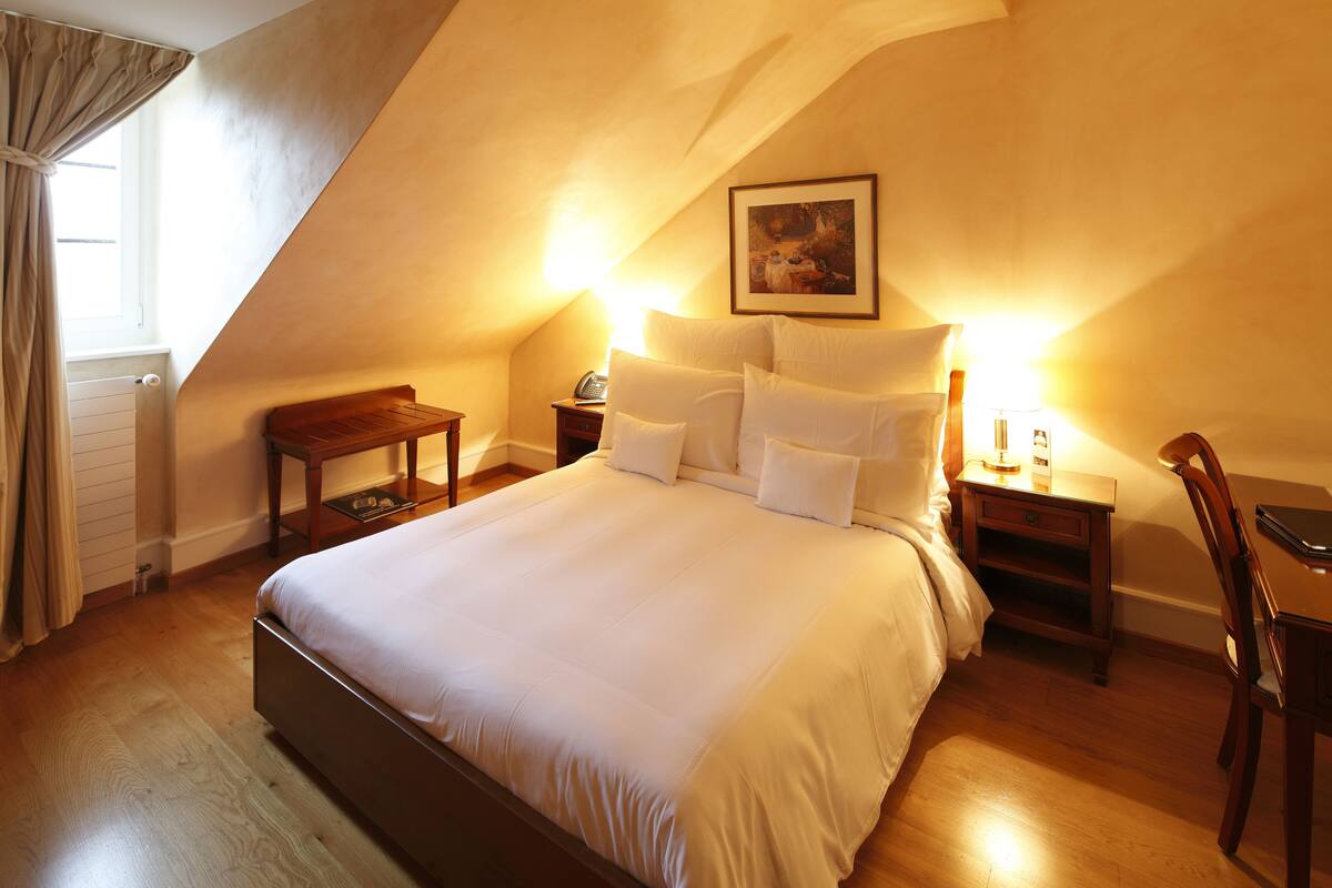 Une chambre à coucher avec un grand lit, des tables de chevet en bois, un bureau et une chaise.