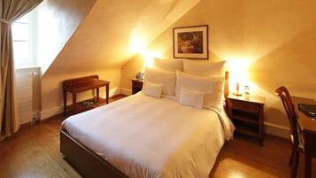 Ein Schlafzimmer mit einem großen Bett, Nachttischen aus Holz, einem Schreibtisch und einem Stuhl.