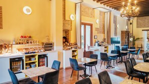 A restaurant with a bar area, multiple tables and chairs, and a variety of food items displayed on shelves. - Hotel Cetina Palacio Ayala Berganza. (Segovia)