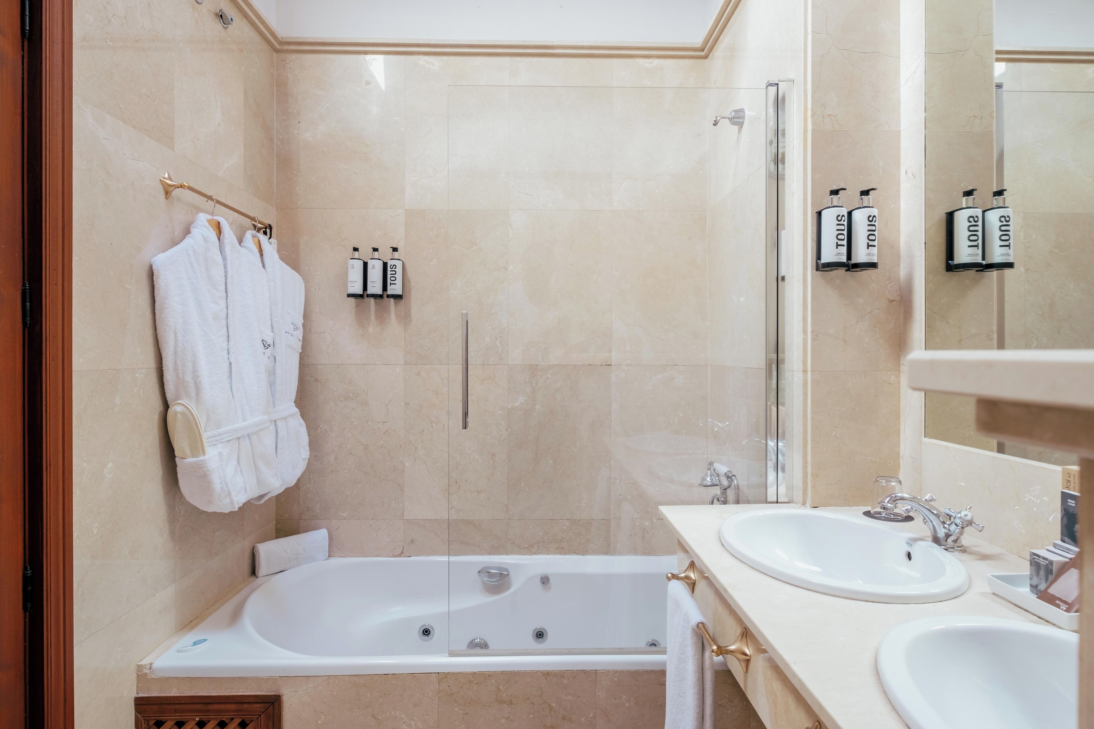 A modern bathroom with a bathtub, two sinks, and a shower area.