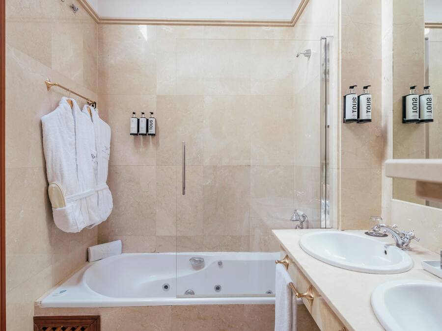 A modern bathroom with a bathtub, two sinks, and a shower area.